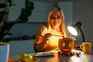 a woman artist prepares for halloween and paints pumpkins photo