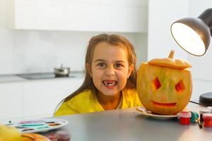 linda niña pequeña con calabaza tallada. foto