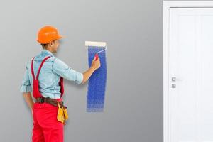 Young worker painting wall in room photo