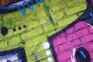 Fragment of graffiti drawings. The old wall decorated with paint stains in the style of street art culture. Colored background texture photo