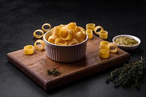 Raw uncooked pasta in a white ceramic bowl with spices and herbs photo