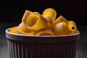 Raw uncooked pasta in a white ceramic bowl with spices and herbs photo