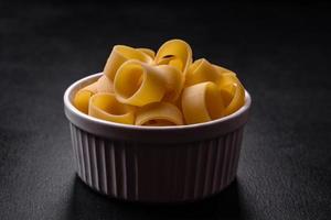 Raw uncooked pasta in a white ceramic bowl with spices and herbs photo