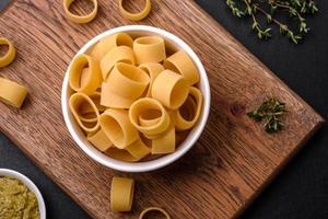 Raw uncooked pasta in a white ceramic bowl with spices and herbs photo