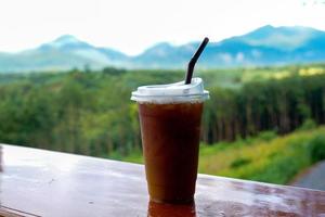 Glass of iced chocolate on wooden background with mountain views, recommended menus in coffee shops. Soft and selective focus. photo