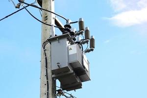 Power transformer installed on electric pole on daytime sky background. Soft and selective focus. photo