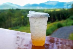 vaso de soda yuzu sobre fondo de madera con vista a la montaña. menú de bebidas en la cafetería. enfoque suave y selectivo. foto