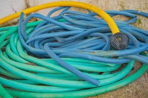 Pile of multi-colored hoses for watering the garden and for water supply, selective focus, plumbing and water dispenser equipment, reuse of materials photo