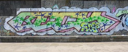 fragmento de dibujos de graffiti. la antigua muralla decorada con manchas de pintura al estilo de la cultura del arte callejero. textura de fondo coloreada en tonos verdes foto