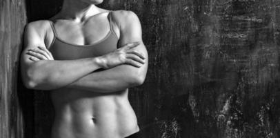 Strong muscular woman is posing against grunge wall photo