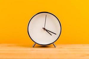 Alarm clock on yellow background, time concept photo