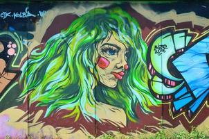 The old wall, painted in color graffiti drawing with aerosol paints. Image of the face of an informal girl with green lush hair photo