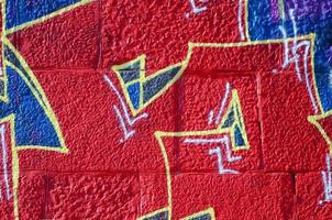 Fragment of graffiti drawings. The old wall decorated with paint stains in the style of street art culture. Colored background texture in warm tones photo
