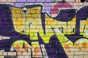 Fragment of graffiti drawings. The old wall decorated with paint stains in the style of street art culture. Colored background texture in warm tones photo