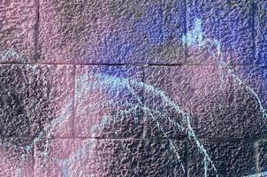 Fragment of graffiti drawings. The old wall decorated with paint stains in the style of street art culture. Colored background texture in purple tones photo