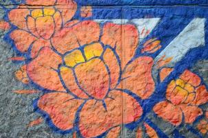 Fragment of graffiti drawings. The old wall decorated with paint stains in the style of street art culture. Orange flower photo