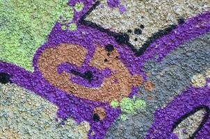 fragmento de dibujos de graffiti. la antigua muralla decorada con manchas de pintura al estilo de la cultura del arte callejero. textura de fondo coloreada en tonos cálidos foto