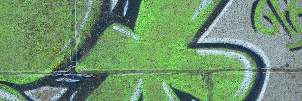 fragmento de dibujos de graffiti. la antigua muralla decorada con manchas de pintura al estilo de la cultura del arte callejero. textura de fondo coloreada en tonos verdes foto