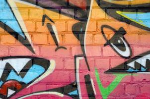 Abstract colorful fragment of graffiti paintings on old brick wall. Street art composition with parts of unwritten letters and multicolored stains. Subcultural background texture photo