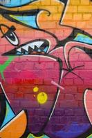 Abstract colorful fragment of graffiti paintings on old brick wall. Street-art composition with parts of wild letters and multicolored stains. Subcultural background texture photo