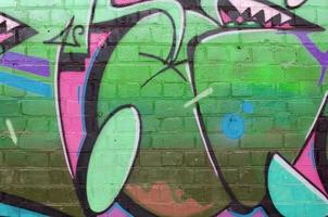 Abstract colorful fragment of graffiti paintings on old brick wall in green colors. Street art composition with parts of unwritten letters and multicolored stains. Subcultural background photo