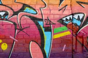 Abstract colorful fragment of graffiti paintings on old brick wall. Street-art composition with parts of wild letters and multicolored stains. Subcultural background texture photo