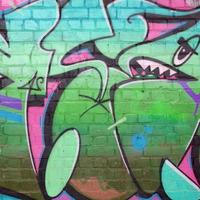 Fragmento colorido abstracto de pinturas de graffiti en la pared de ladrillo antiguo en colores rosa y verde. composición de arte callejero con partes de letras no escritas y manchas multicolores foto