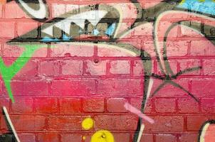 Abstract colorful fragment of graffiti paintings on old brick wall. Street art composition with parts of unwritten letters and multicolored stains. Subcultural background texture photo