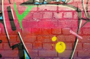 Abstract colorful fragment of graffiti paintings on old brick wall. Street-art composition with parts of wild letters and multicolored stains. Subcultural background texture photo
