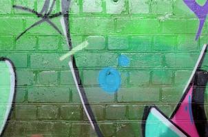 Abstract colorful fragment of graffiti paintings on old brick wall in green colors. Street art composition with parts of unwritten letters and multicolored stains. Subcultural background photo