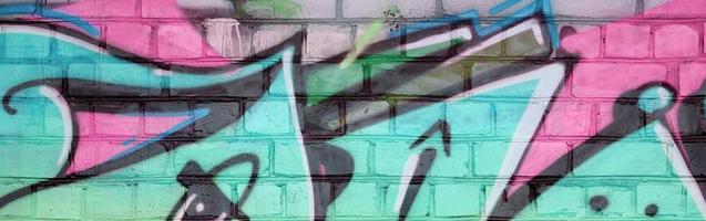 Abstract colorful fragment of graffiti paintings on old brick wall in pink and green colors. Street art composition with parts of unwritten letters and multicolored stains photo