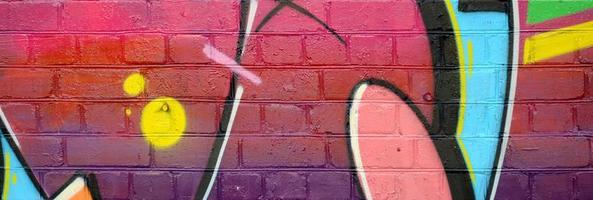 Abstract colorful fragment of graffiti paintings on old brick wall. Street-art composition with parts of wild letters and multicolored stains. Subcultural background texture photo