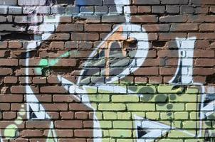 fragmento de dibujos de graffiti. la antigua muralla decorada con manchas de pintura al estilo de la cultura del arte callejero. textura de fondo coloreada en tonos cálidos foto