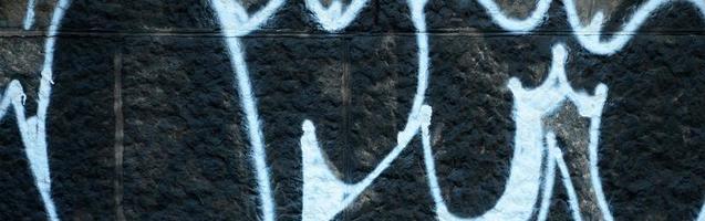 Fragment of graffiti drawings. The old wall decorated with paint stains in the style of street art culture. Colored background texture photo