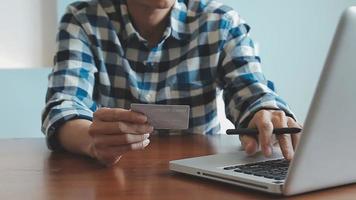 mãos segurando um cartão de crédito e usando o laptop. compras online video