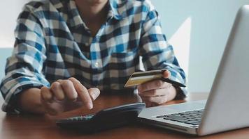 mãos segurando um cartão de crédito e usando o laptop. compras online video