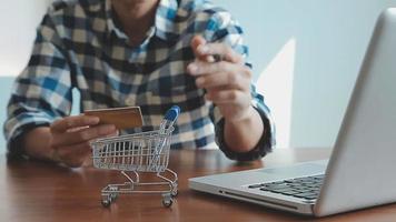 mãos segurando um cartão de crédito e usando o laptop. compras online video