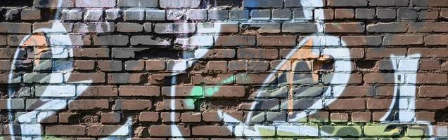 fragmento de dibujos de graffiti. la antigua muralla decorada con manchas de pintura al estilo de la cultura del arte callejero. textura de fondo coloreada en tonos cálidos foto