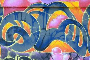 Fragment of graffiti drawings. The old wall decorated with paint stains in the style of street art culture. Colored background texture in warm tones photo