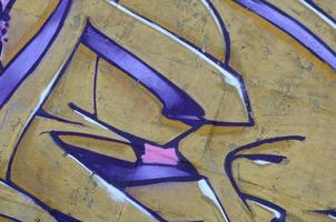 Fragment of graffiti drawings. The old wall decorated with paint stains in the style of street art culture. Colored background texture in purple tones photo