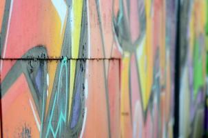 fragmento de dibujos de graffiti. la antigua muralla decorada con manchas de pintura al estilo de la cultura del arte callejero. textura de fondo coloreada en tonos cálidos foto