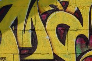 Fragment of graffiti drawings. The old wall decorated with paint stains in the style of street art culture. Colored background texture in warm tones photo