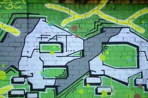 Fragment of graffiti drawings. The old wall decorated with paint stains in the style of street art culture. Colored background texture in green tones photo