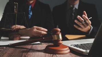 Business and lawyers discussing contract papers with brass scale on desk in office. Law, legal services, advice, justice and law concept picture with film grain effect video