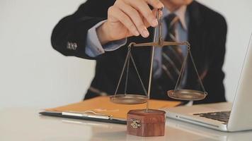 Business and lawyers discussing contract papers with brass scale on desk in office. Law, legal services, advice, justice and law concept picture with film grain effect video