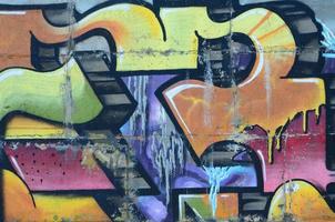 Fragment of graffiti drawings. The old wall decorated with paint stains in the style of street art culture. Colored background texture in warm tones photo