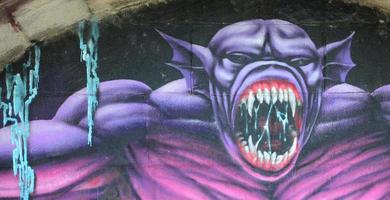 fragmento de dibujos de graffiti. la antigua muralla decorada con manchas de pintura al estilo de la cultura del arte callejero. monstruo aterrador púrpura foto