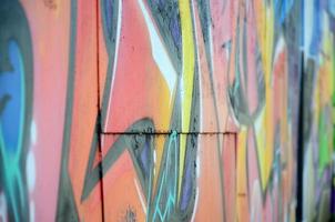 Fragment of graffiti drawings. The old wall decorated with paint stains in the style of street art culture. Colored background texture in warm tones photo