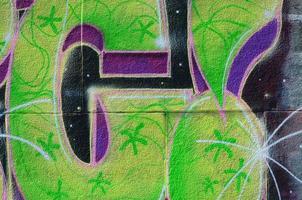 Fragment of graffiti drawings. The old wall decorated with paint stains in the style of street art culture. Colored background texture in green tones photo