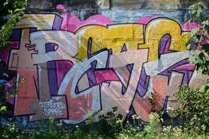 fragmento de dibujos de graffiti. la antigua muralla decorada con manchas de pintura al estilo de la cultura del arte callejero. textura de fondo coloreada en tonos cálidos foto